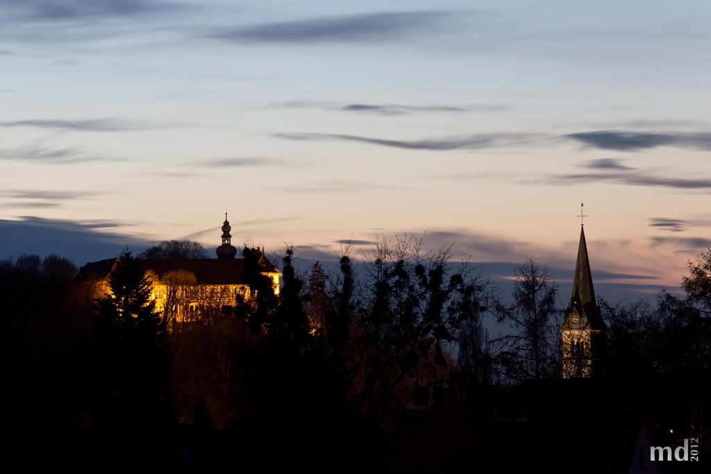 Schloss Herzberg im Gegenlicht der Abendsonne (mit Kirchturm der katholischen Kirche St. Josef)